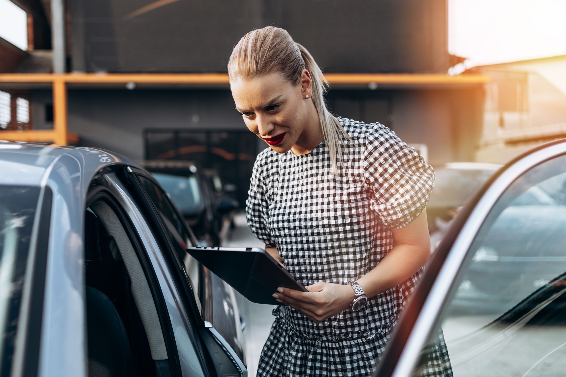 Female used car dealer checking vehicle before customer