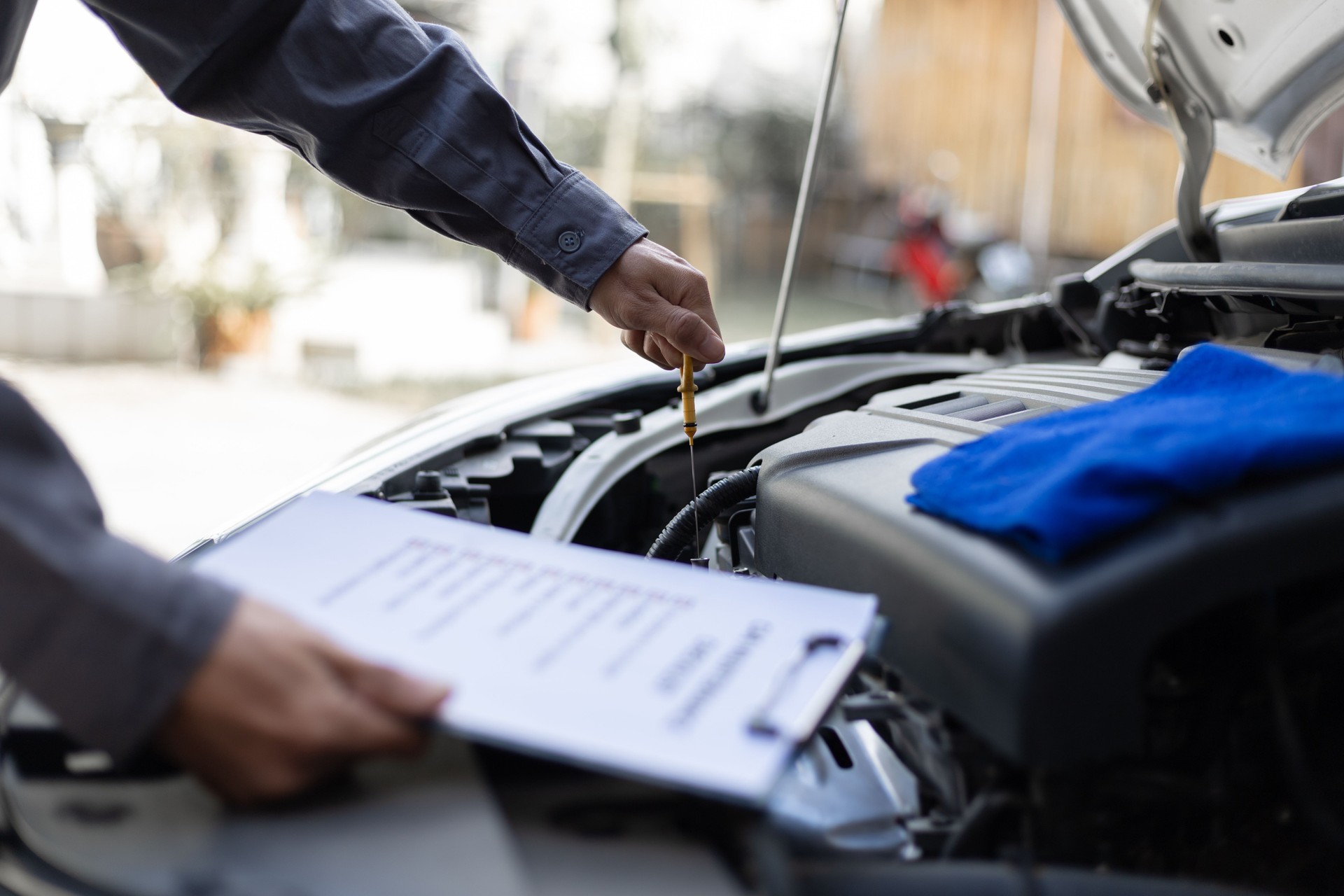 A mechanic checks the car and engine oil.