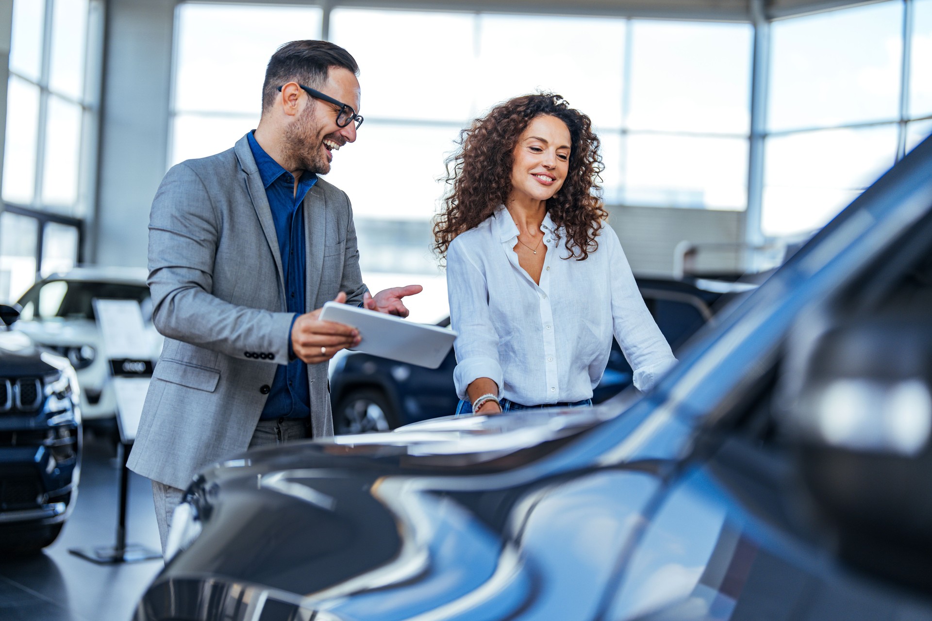 Smiling Car Salesman Assisting Woman at Dealership